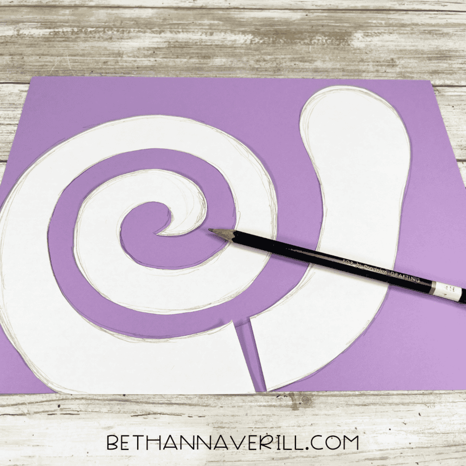 Snail shell spiral drawn on purple construction paper with a pencil.