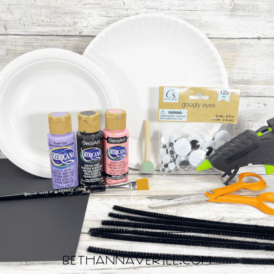 Supplies for spider and web craft, including paper plates, paint, pipe cleaners, googly eyes, scissors, and glue.