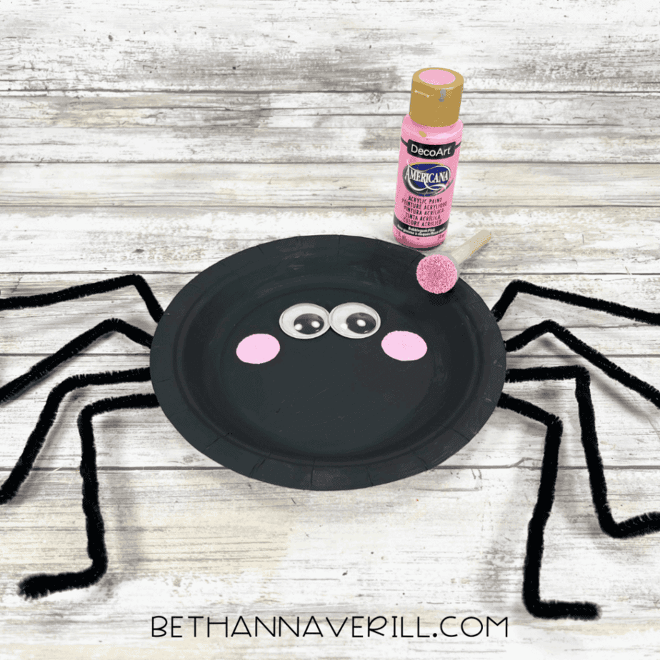 Pink cheeks painted onto spider face under googly eyes.