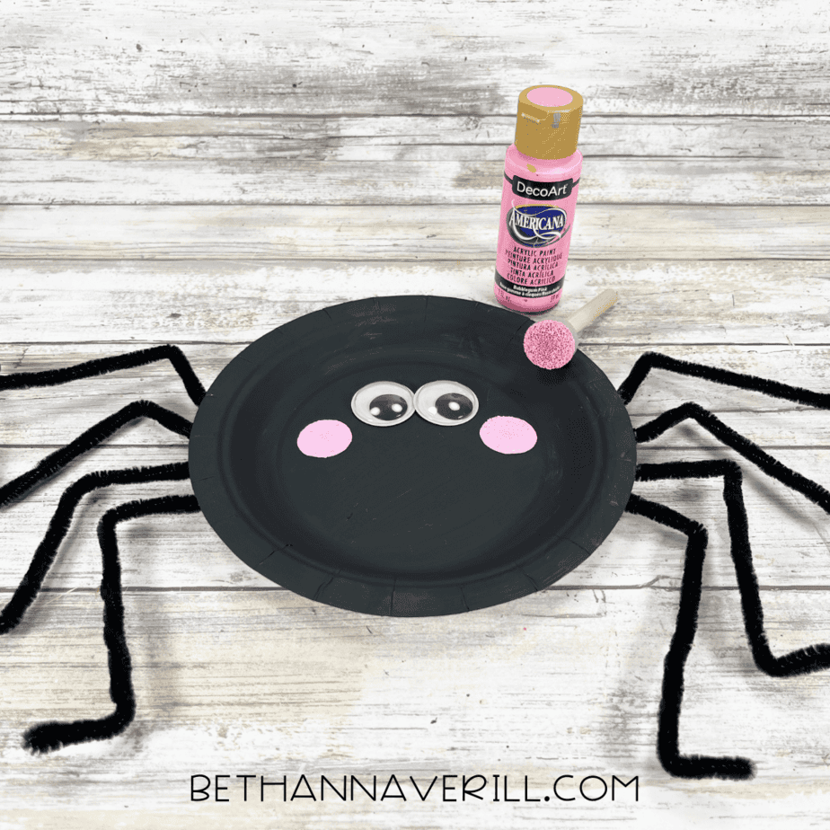 Pink cheeks painted onto spider face under googly eyes.