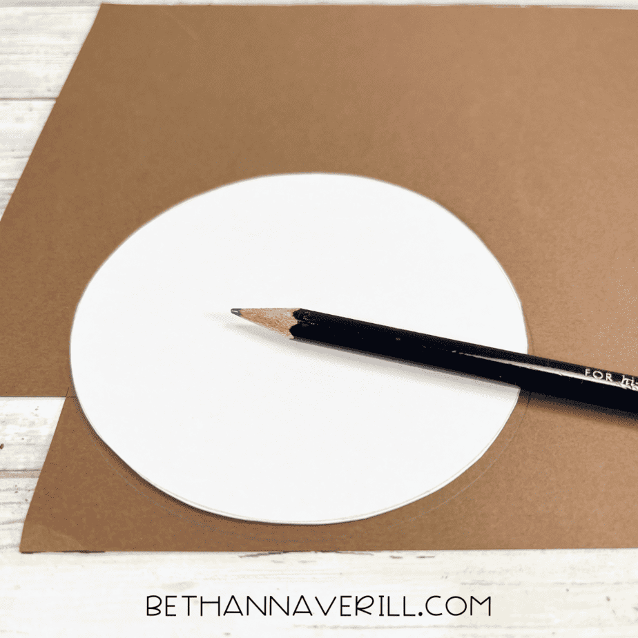 White circle template traced onto brown construction paper with a pencil.