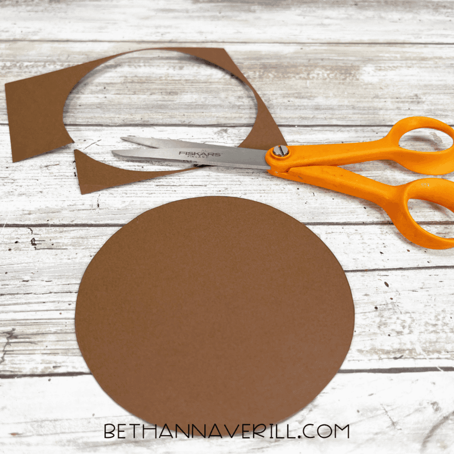 Brown circle cut out with scissors on a wooden surface.