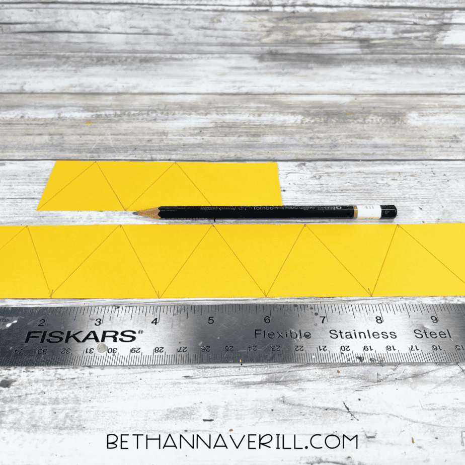 Yellow construction paper with triangle shapes drawn using a ruler and pencil.