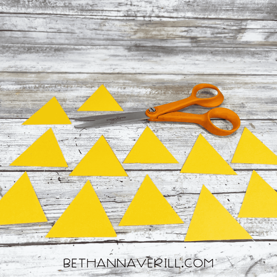 Cut-out yellow triangles scattered on a table with scissors.