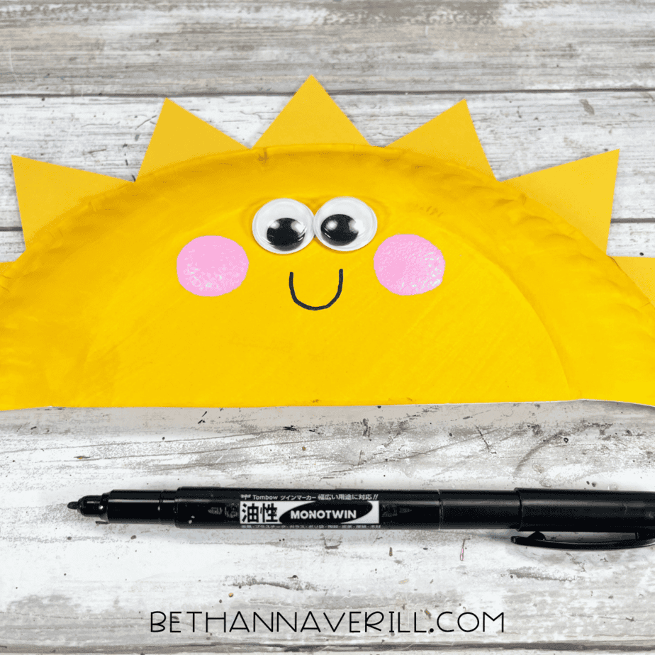 Sunshine craft with a black smile drawn on the yellow plate.