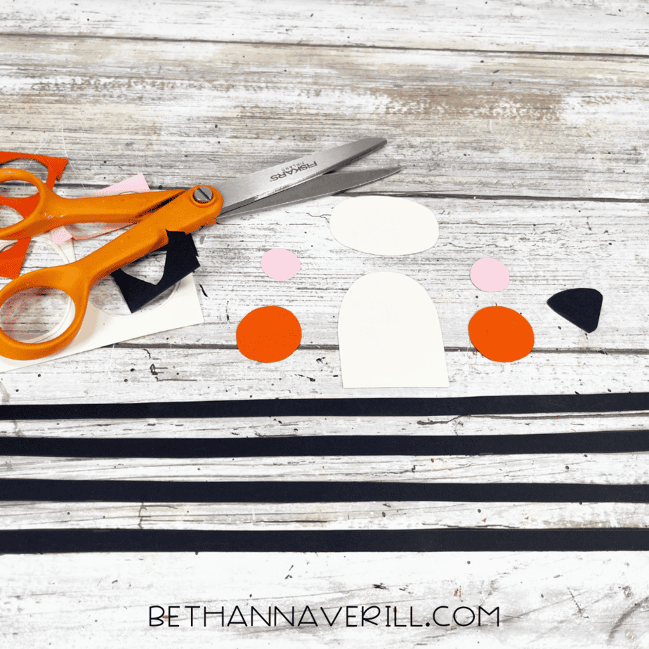 Cut-out paper shapes including ovals, circles, and stripes for tiger craft pieces.