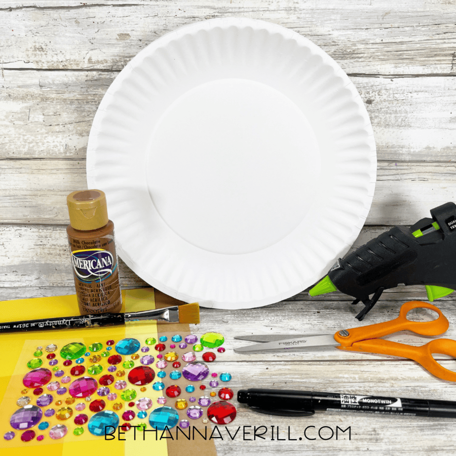 Craft supplies for treasure chest craft including paper plates, paint, gems, and scissors.