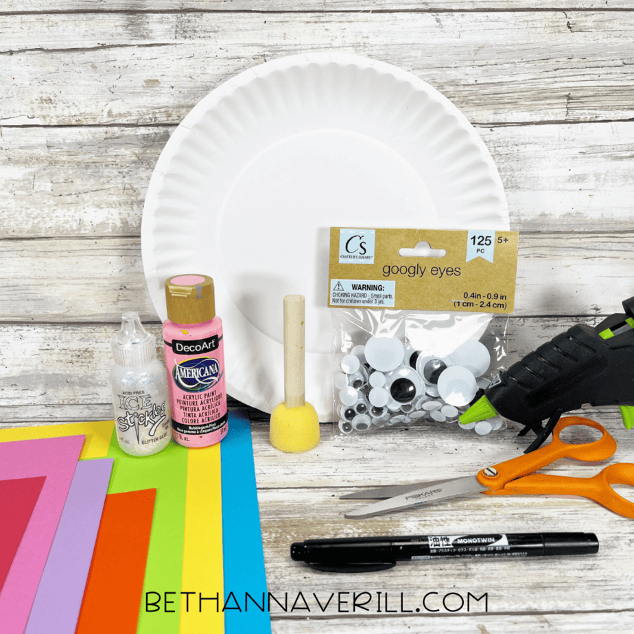Unicorn paper plate craft materials including paint, googly eyes, paper, scissors, and glue.
