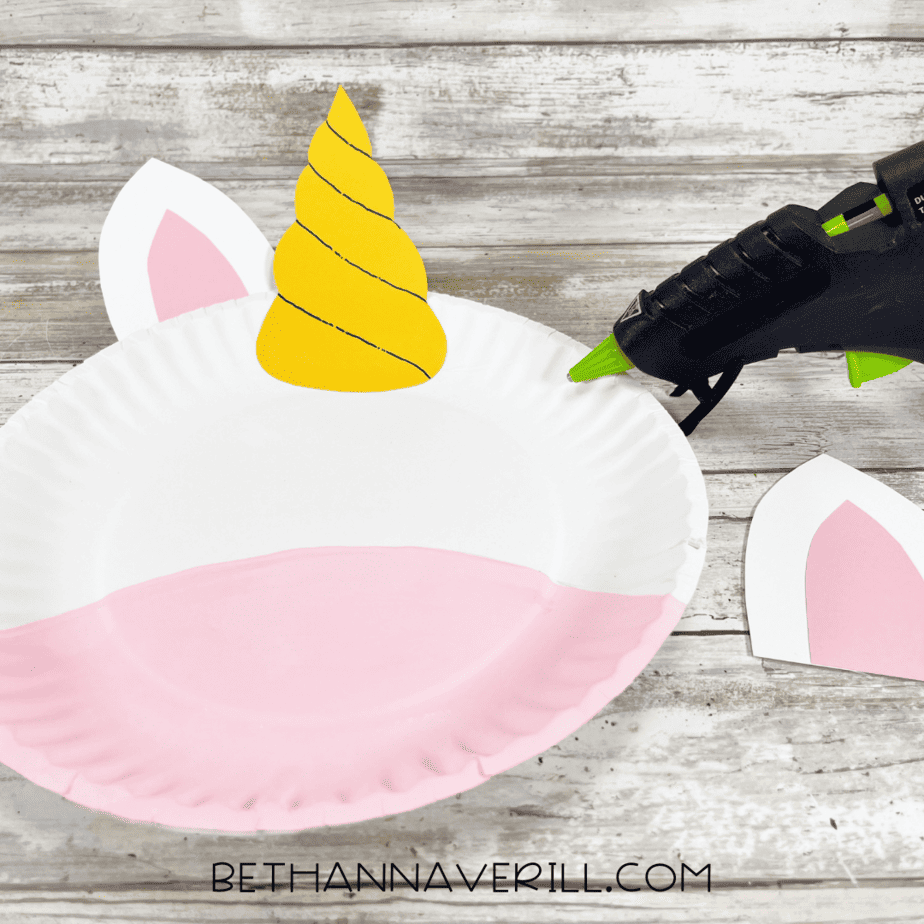 Paper plate with glued-on unicorn horn and one ear attached.