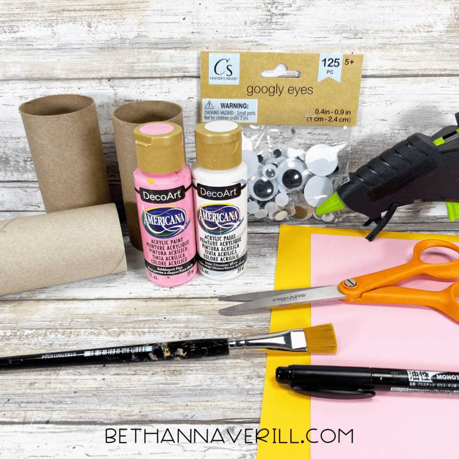 Materials for unicorn paper roll craft including paint, toilet paper rolls, googly eyes, scissors, and paper.
