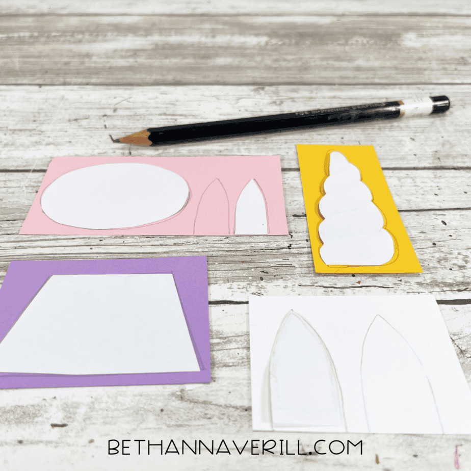 Unicorn craft templates drawn on colored paper, including horn, ears, snout, and mane pieces.