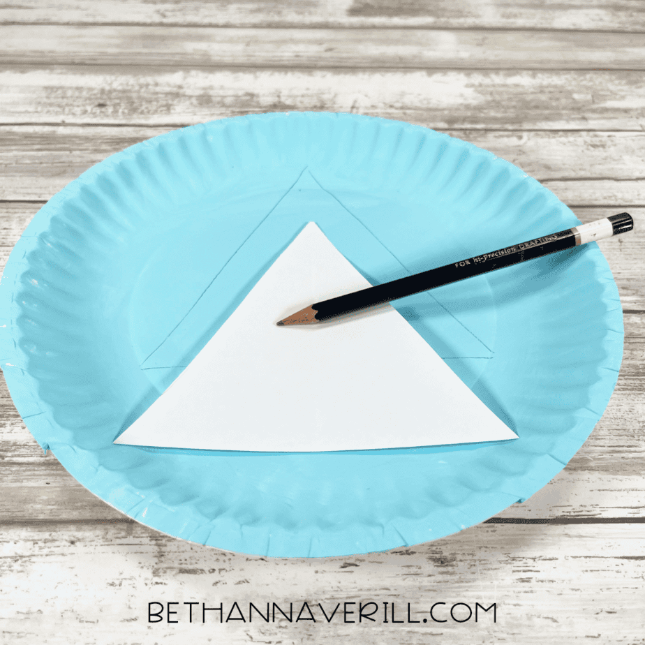 Paper plate with triangle tree shape drawn using a pencil and white template.