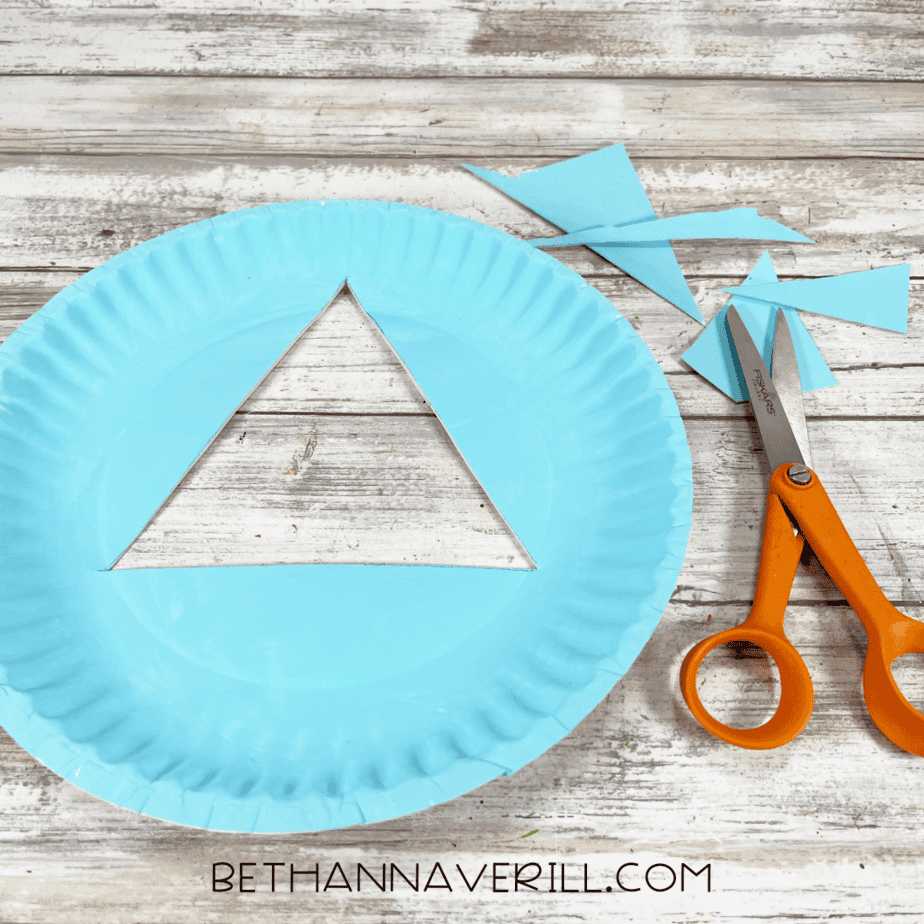Paper plate with triangle tree section cut out using scissors.