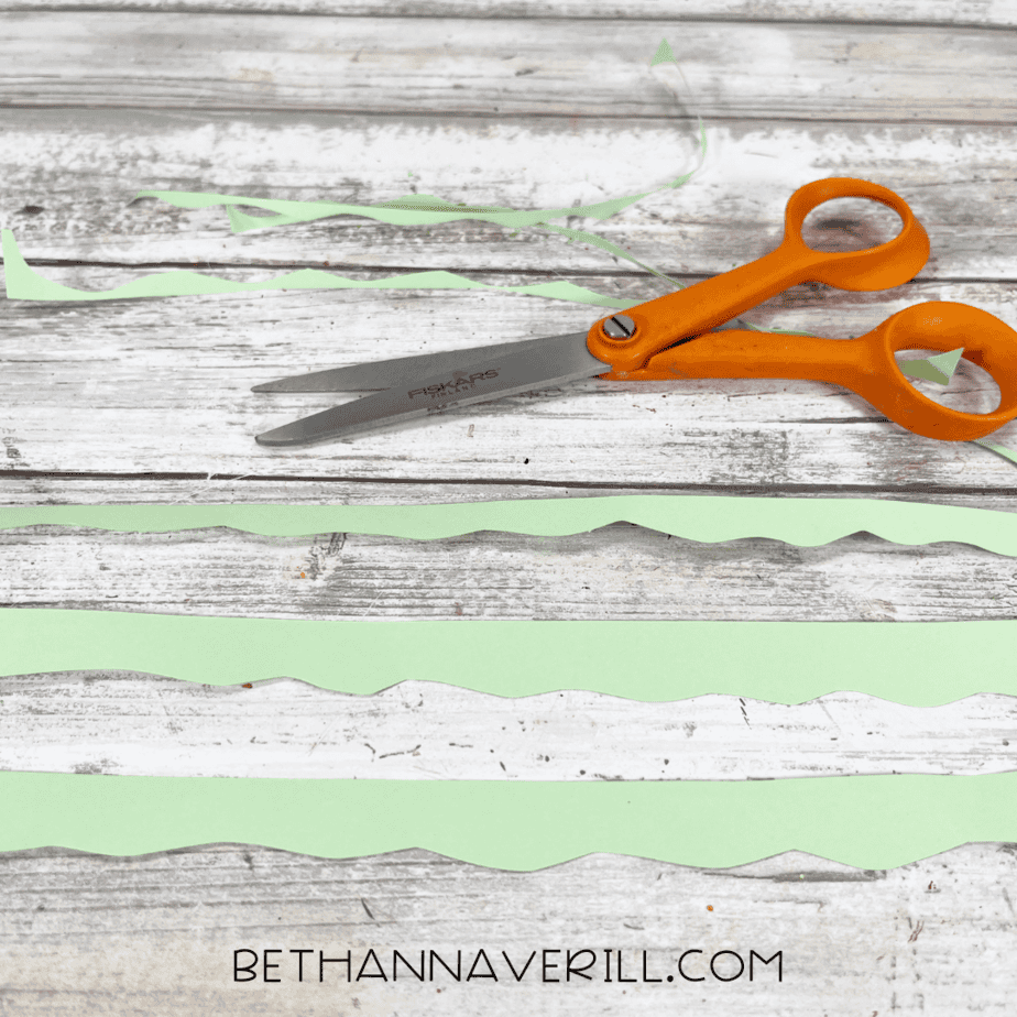 Green paper strips with wavy edges cut to look like tree branches.