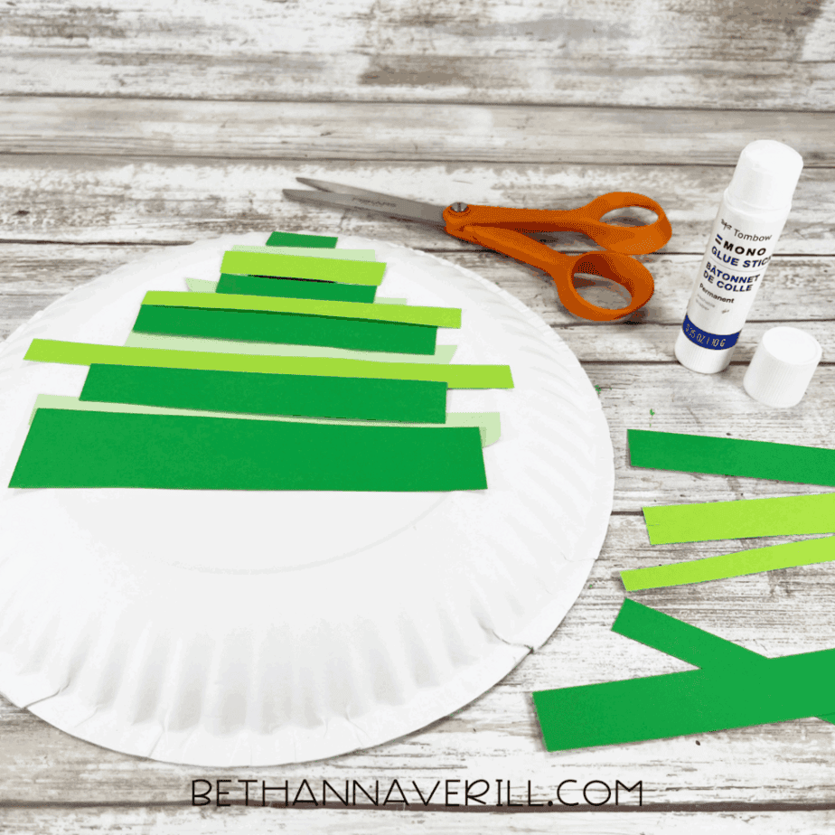Paper plate showing multiple green strips layered behind triangle shape for tree.