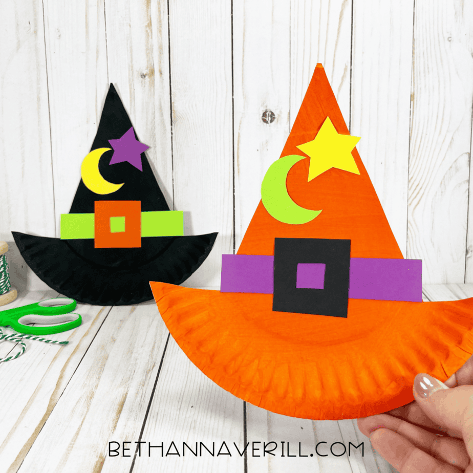 Finished witch hat crafts, one orange and one black, displayed upright on a wooden background.