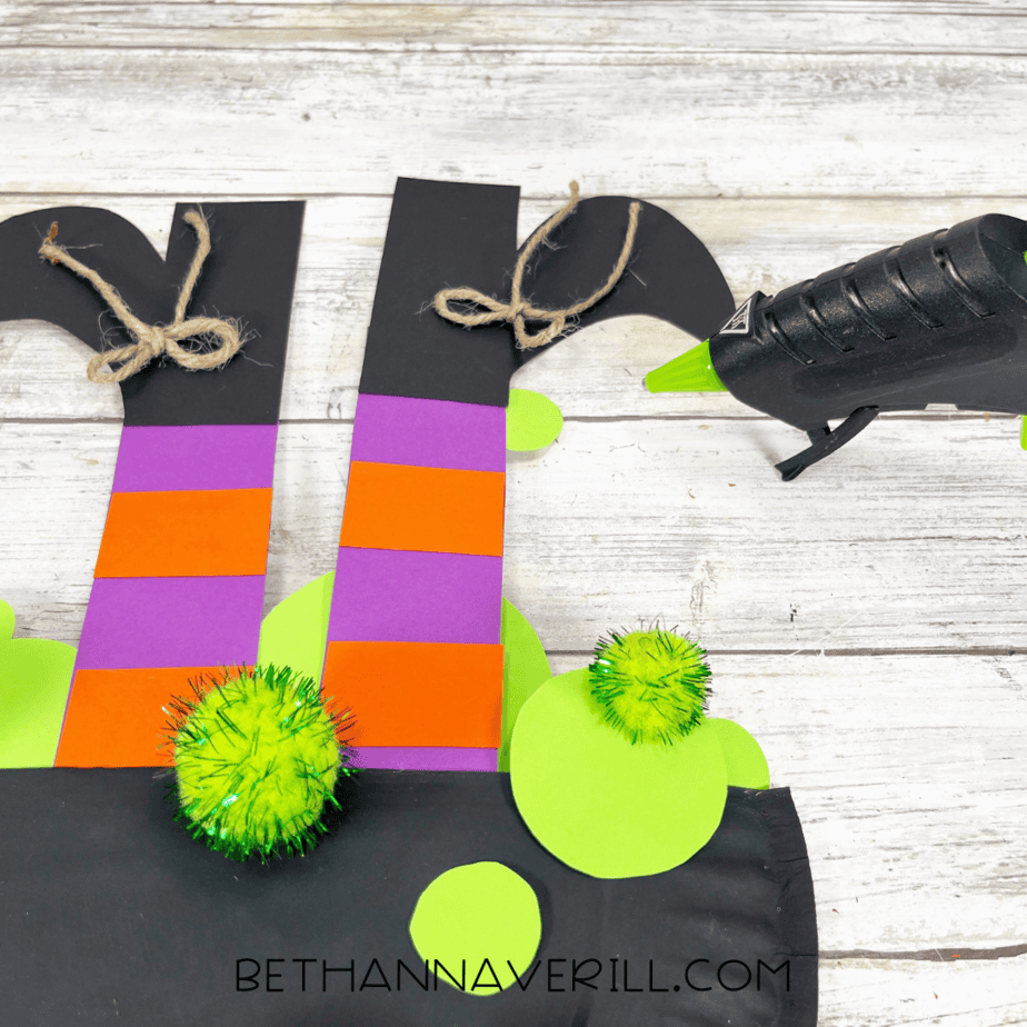 Witch legs craft decorated with twine bows and green pom poms for bubbles.