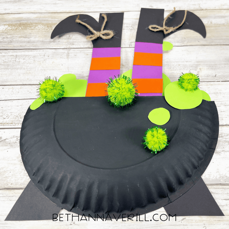 Finished witch legs paper plate craft showing witch legs sticking out of cauldron.