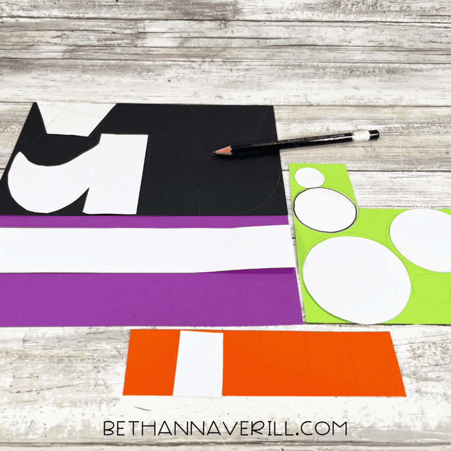Paper templates traced onto black, purple, orange, and green construction paper.
