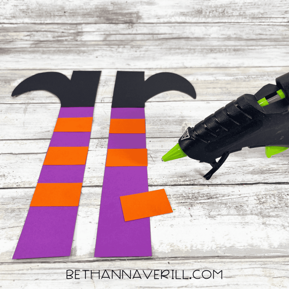 Purple paper strips with orange rectangles glued on to make striped stockings.