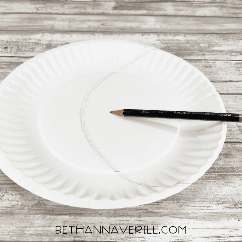 Paper plate with a curved pencil line drawn across the middle for moon and sky sections.