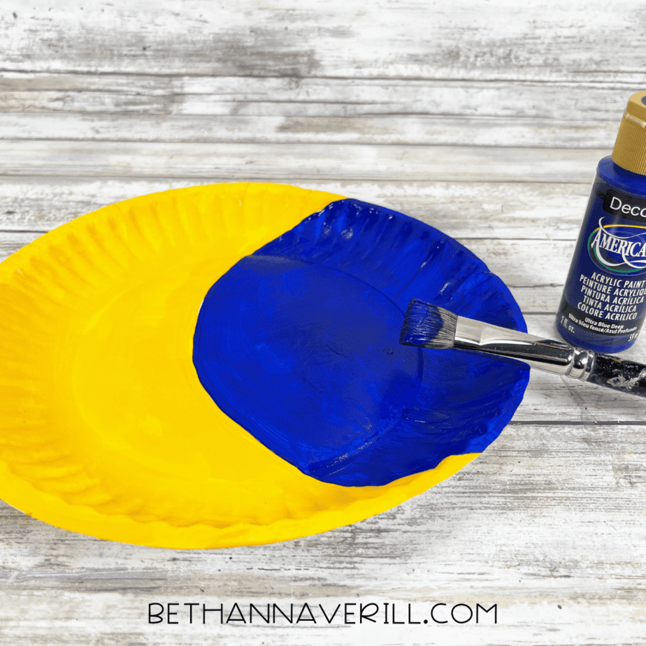 Paper plate with one half painted yellow and the other being painted blue for night sky.