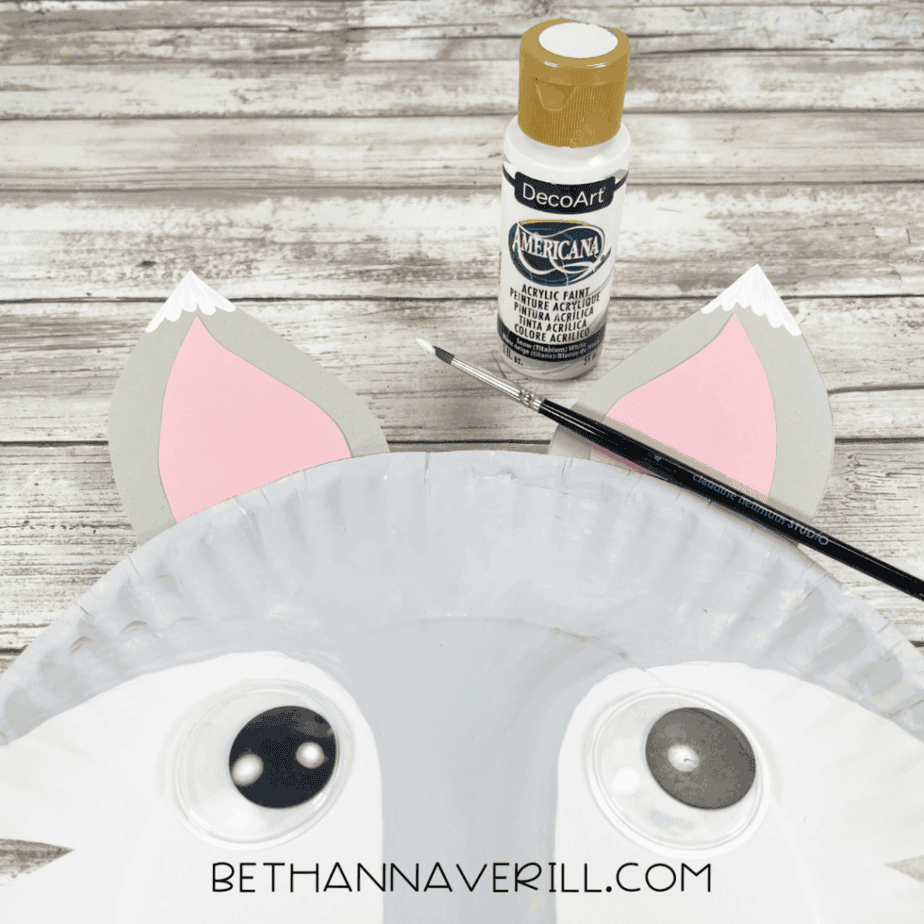 White paint added to the top edges of both ears to mimic snowy fur, with a small brush and white acrylic paint nearby.