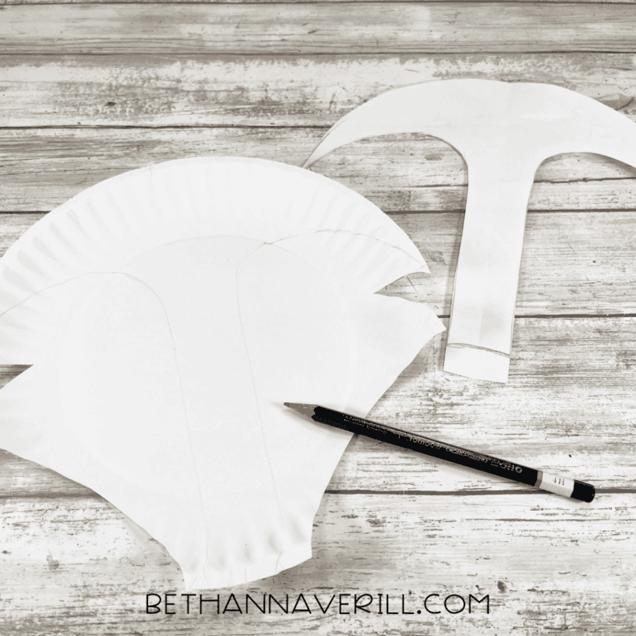 A cut paper plate forming the Arctic fox head shape, with pencil-traced details, next to a paper pattern template.