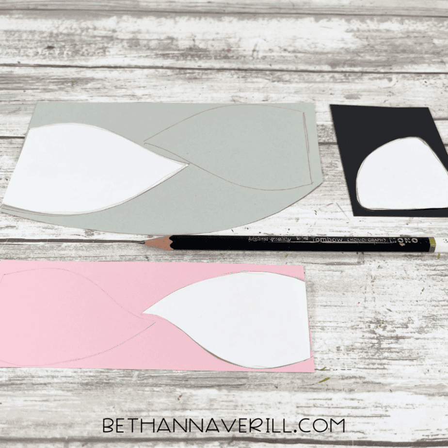 White Arctic fox face pattern pieces traced onto gray, pink, and black cardstock with a pencil.