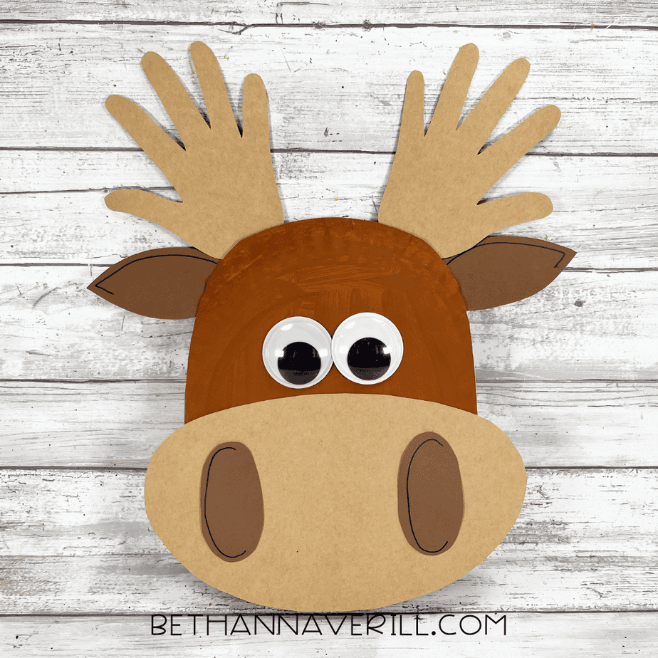 Finished paper plate moose craft with googly eyes, cardstock muzzle, ears, and handprint antlers.
