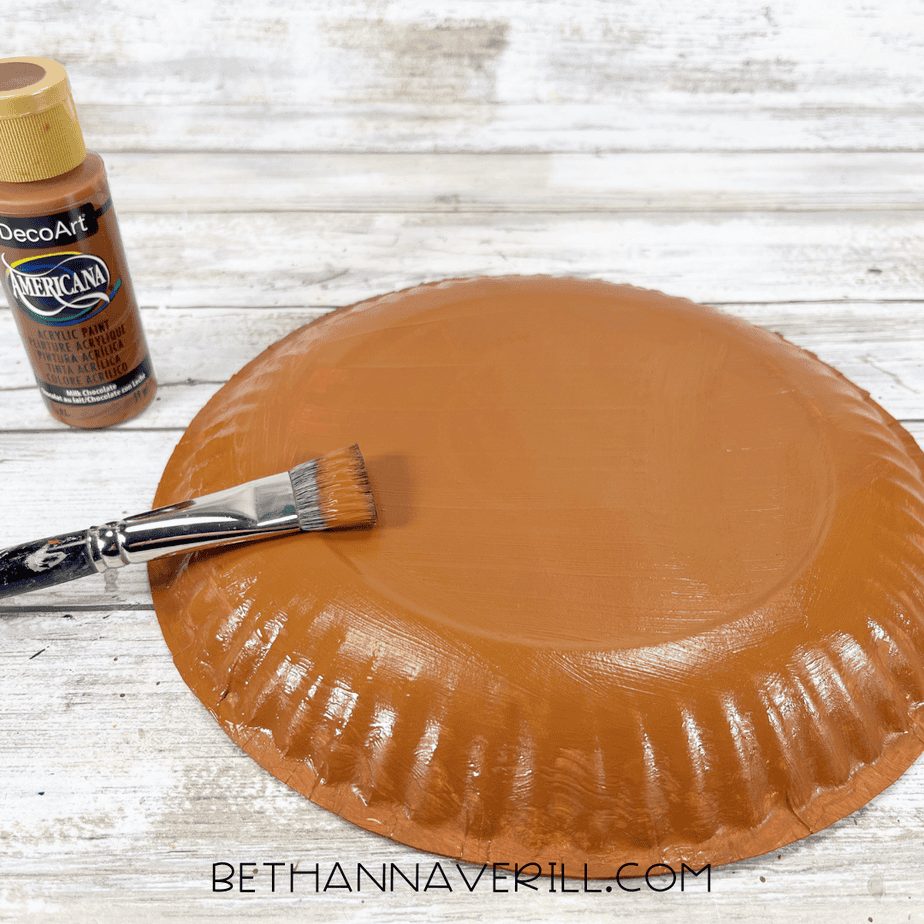 Paper plate flipped upside down and painted medium brown with a wide paintbrush.