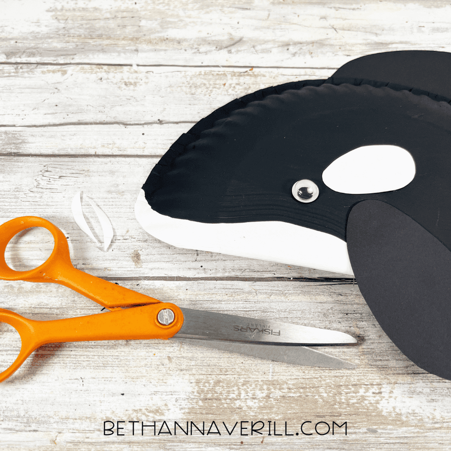 Close-up of orca face details being adjusted with scissors beside the craft.