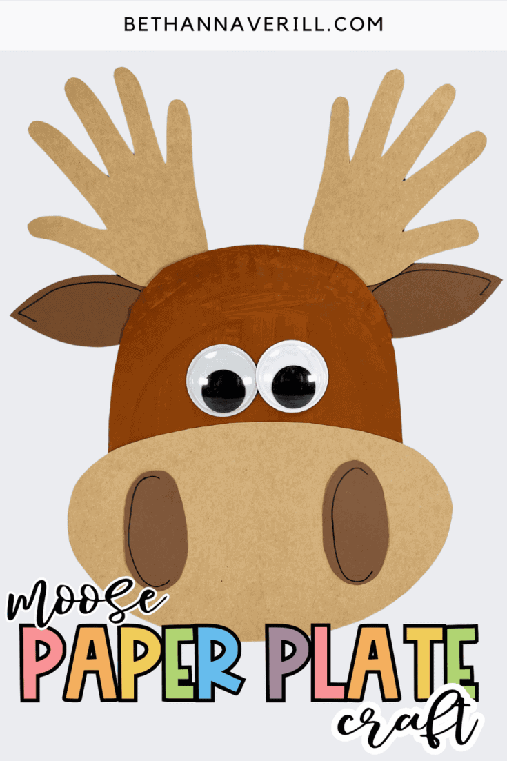 A finished paper plate moose craft with brown painted face, oversized googly eyes, handprint antlers, and a large oval snout, displayed on a bright white background with the text “Moose Paper Plate Craft” at the bottom.