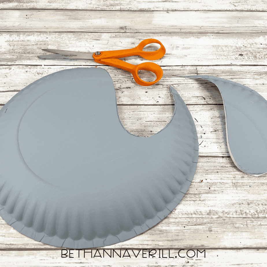 A cut gray paper plate showing the seal body shape with a large section removed and scissors nearby.