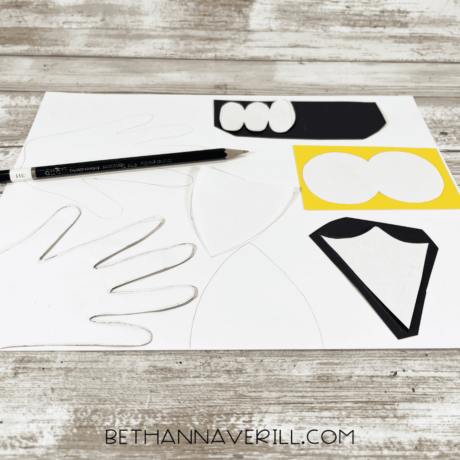 Snowy owl paper plate craft templates traced onto white, yellow, and black cardstock with a pencil.