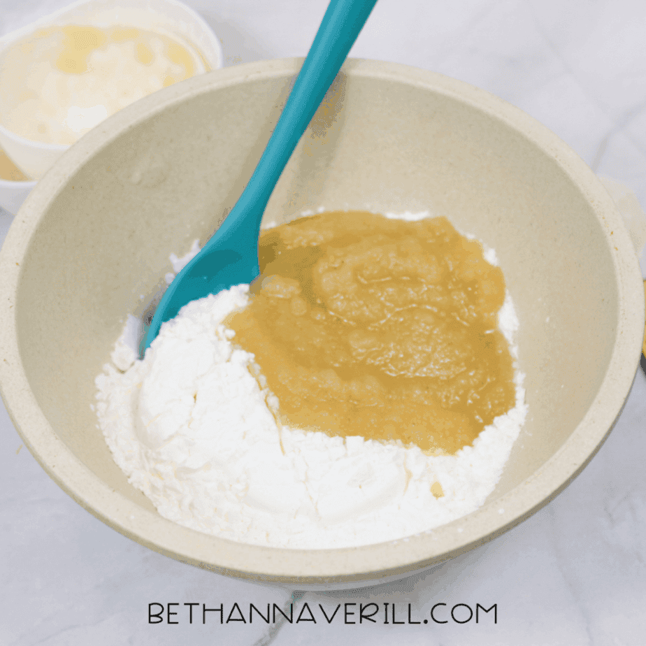 Applesauce and cornstarch added together in a mixing bowl with a teal spoon.
