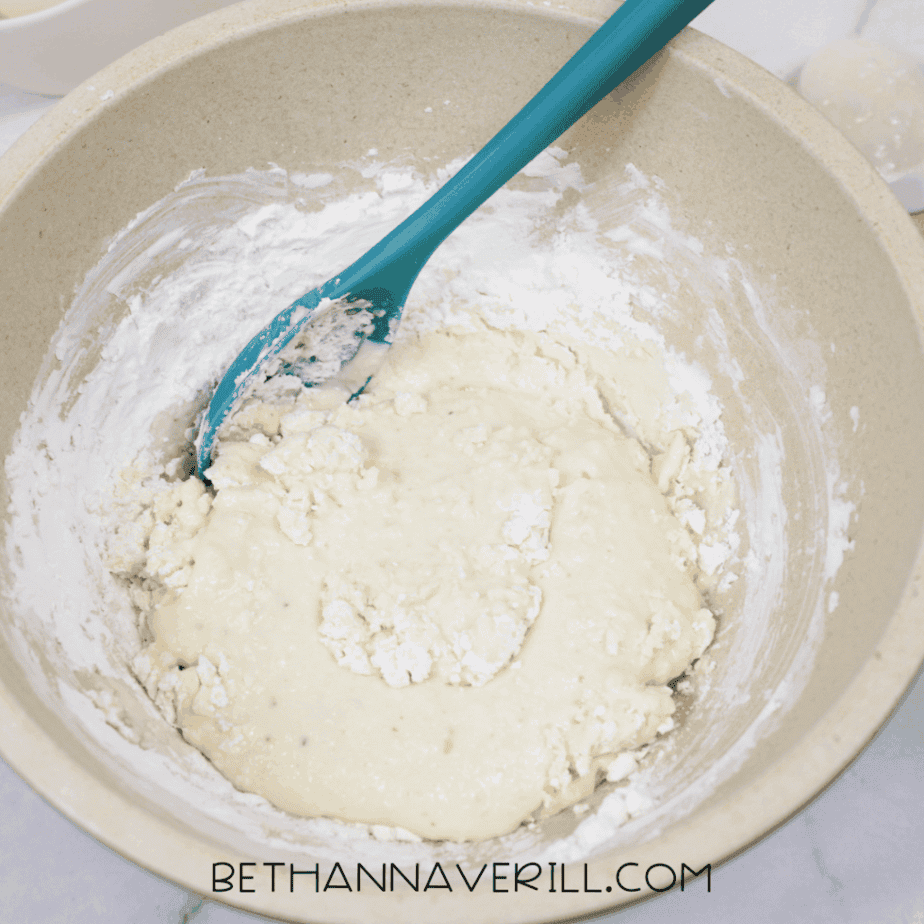 Partially mixed applesauce slime with thick, lumpy texture forming in the bowl.