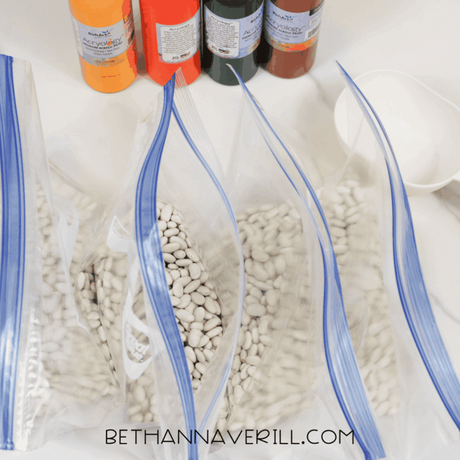 Dried white beans divided into zip-top bags, ready to be dyed for an autumn sensory bin activity.