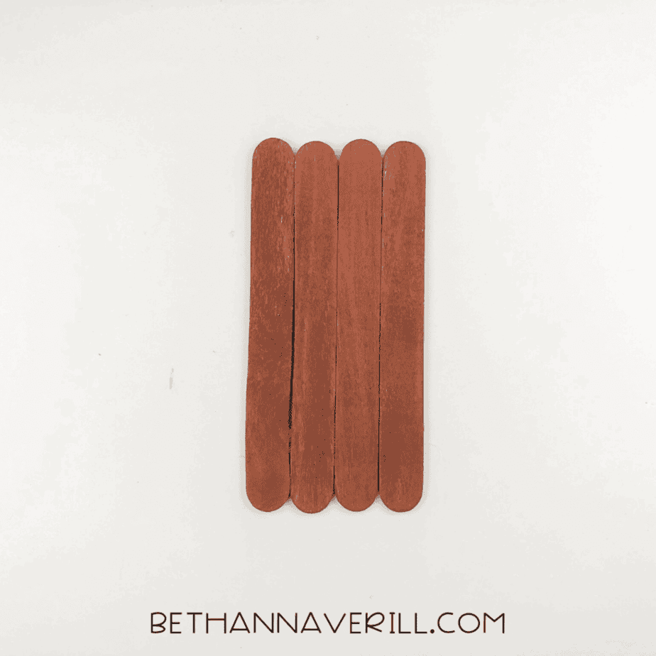 Four brown-painted jumbo craft sticks lined up vertically to form a rectangle shape.