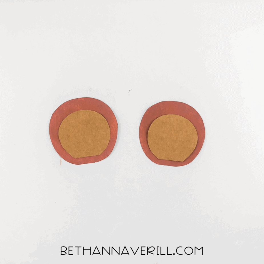 Two layered ear pieces made from brown and tan cardstock placed side by side.