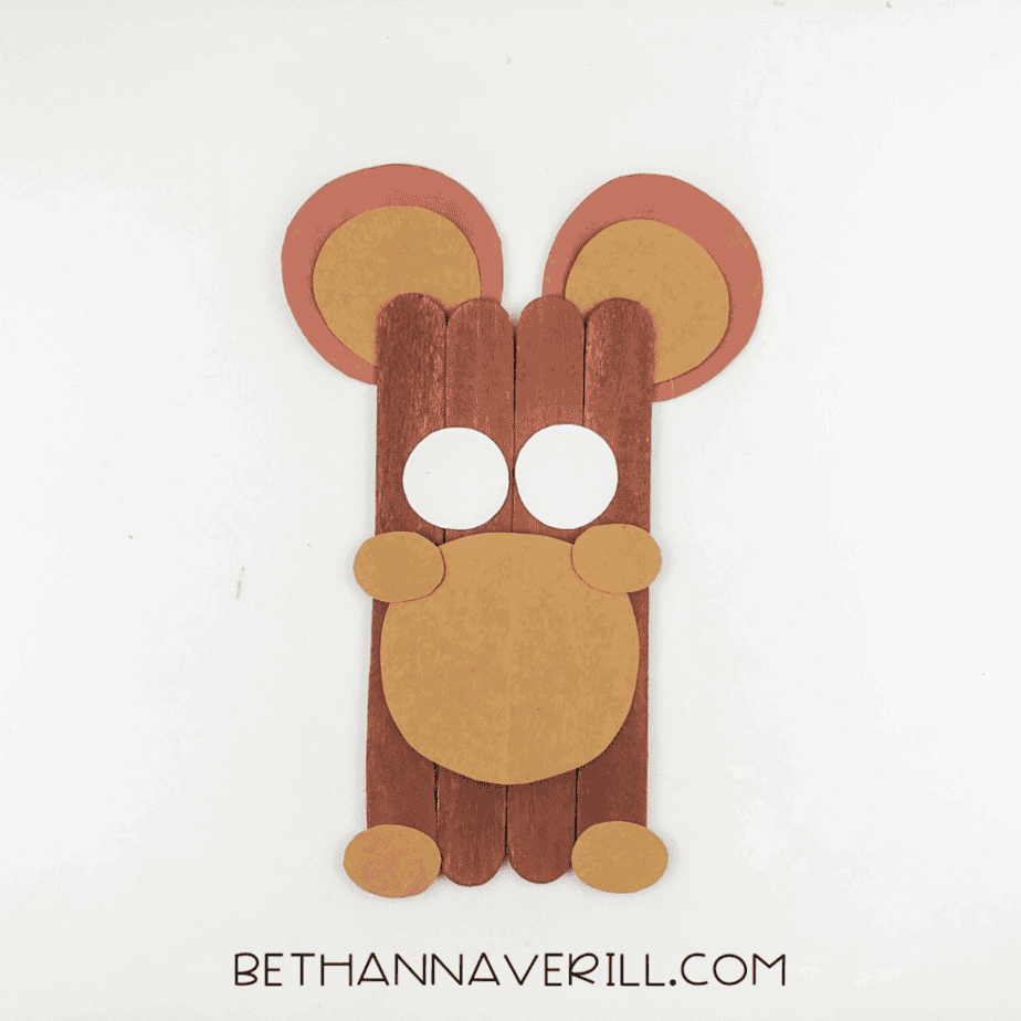Small tan oval shapes attached to the sides of the muzzle and near the bottom of the craft stick base.
