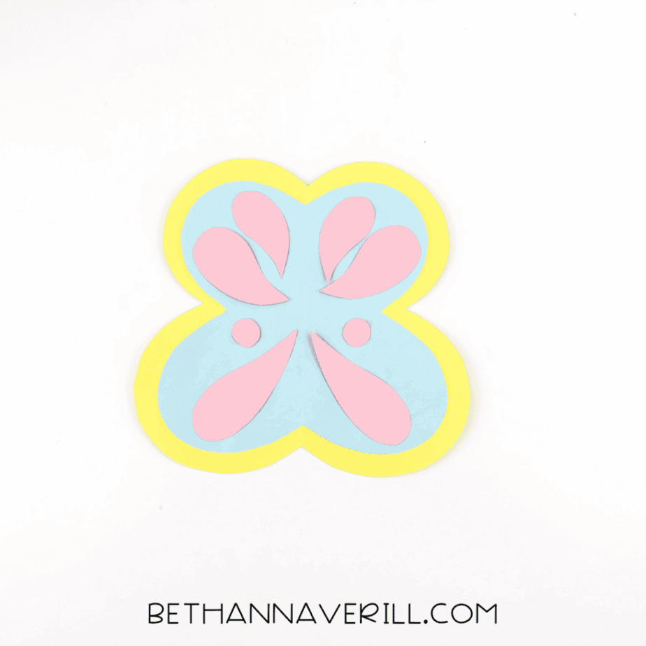 Fully assembled butterfly wing piece made from layered yellow, blue, and pink cardstock on a white background.