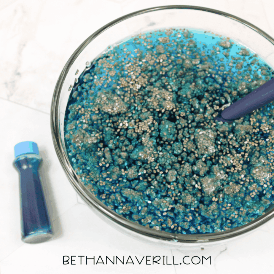 Glass bowl filled with hydrated chia seeds tinted blue, shown from above with a spoon resting inside.