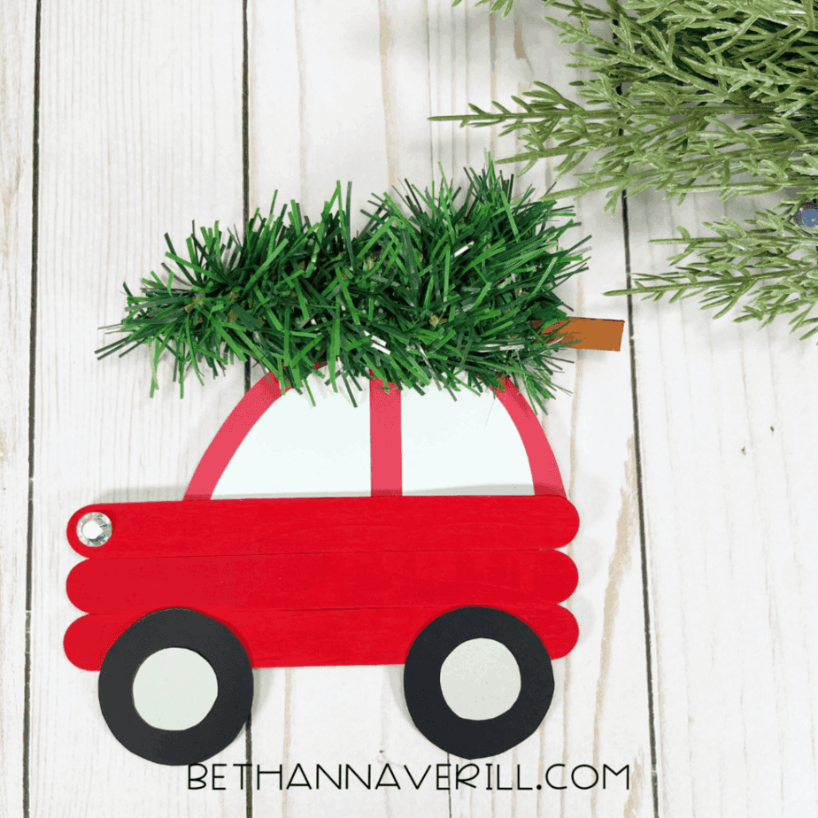 Finished red popsicle stick Christmas car with paper wheels and a tree on top