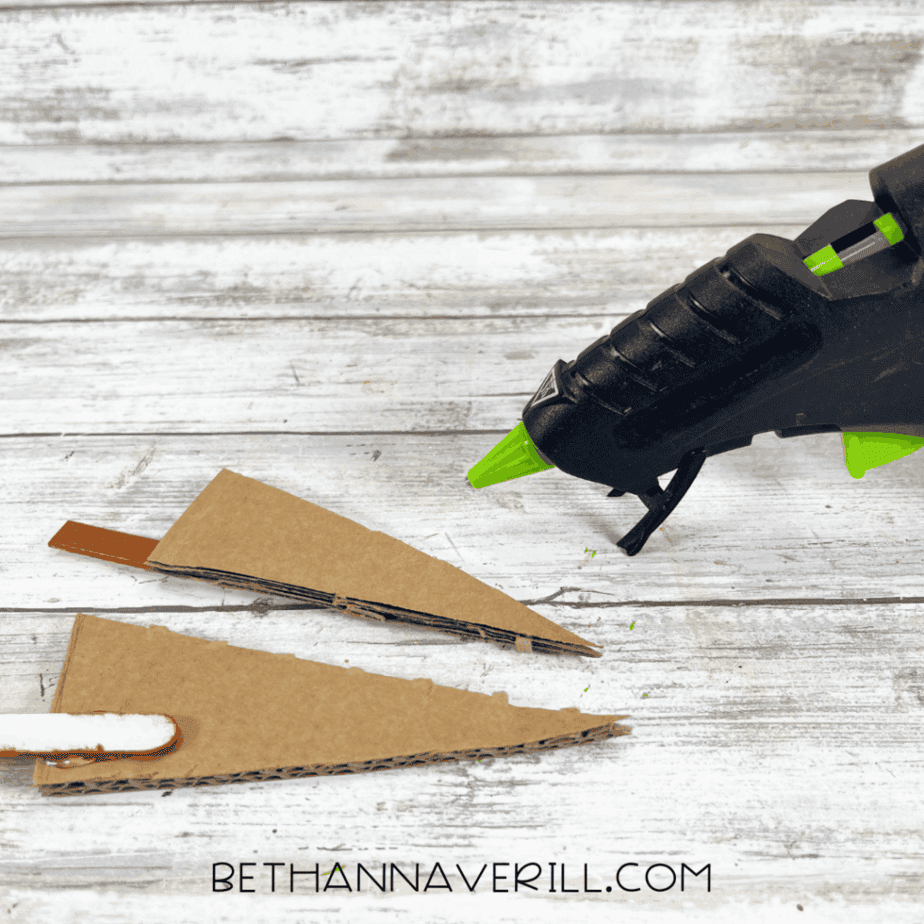 Cardboard triangle pieces glued to popsicle sticks to create a tree stand for a Christmas car craft