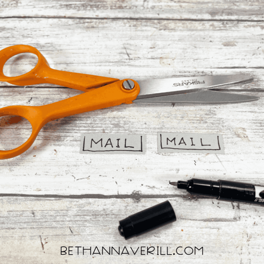 Small cardstock labels reading “mail” next to scissors and a black marker