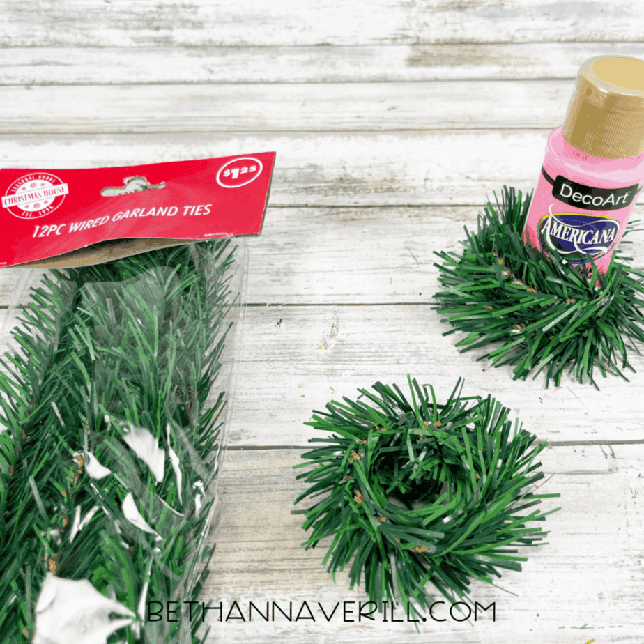 Faux greenery garland pieces cut into small wreath shapes for a Christmas door craft