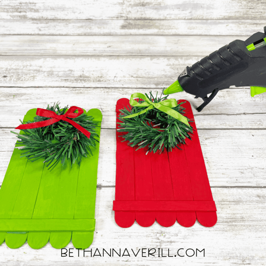 Popsicle stick doors decorated with small wreaths and ribbon bows using hot glue