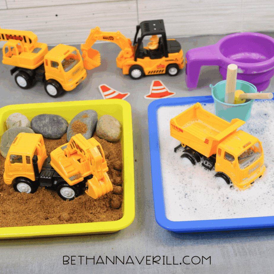 Toy dump truck tipping sand into a pile inside a yellow sensory bin with rocks.
