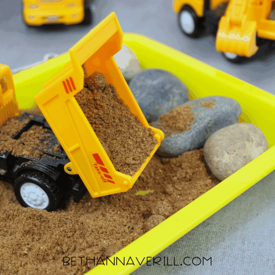 Toy construction truck covered in bubbles while being washed in a water sensory tray.